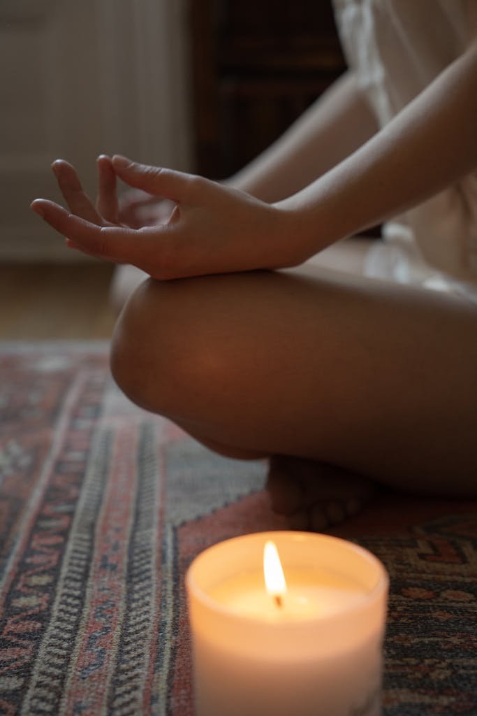 A person meditating indoors with a lit candle. Perfect for relaxation and wellness themes.